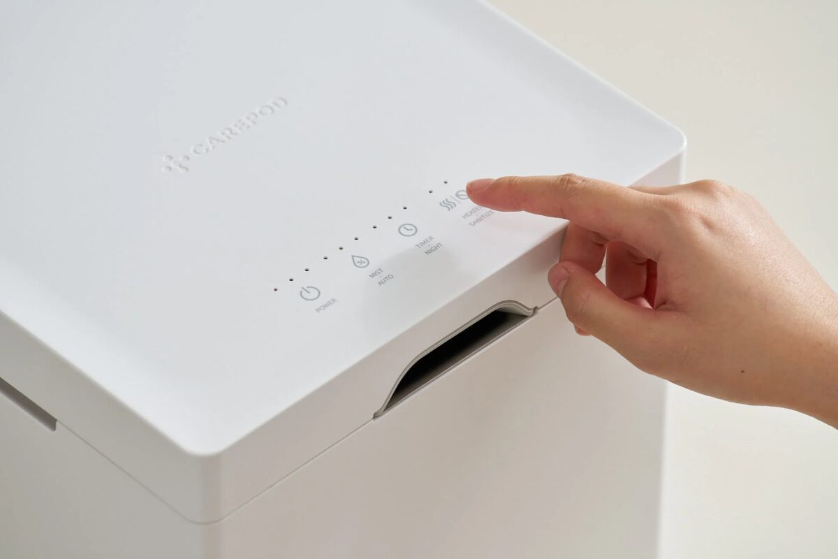 白い家電製品の操作パネルに指が触れ、設定を変更している様子