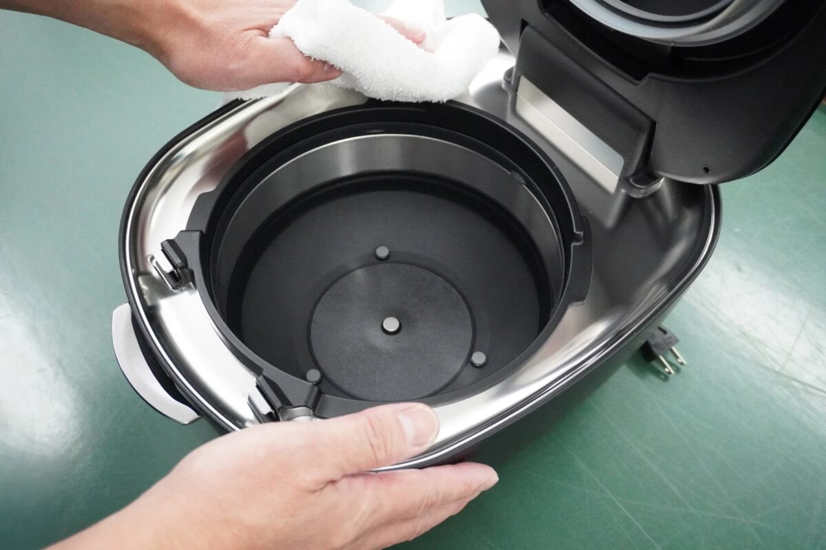 炊飯器の内部をタオルで拭く様子
