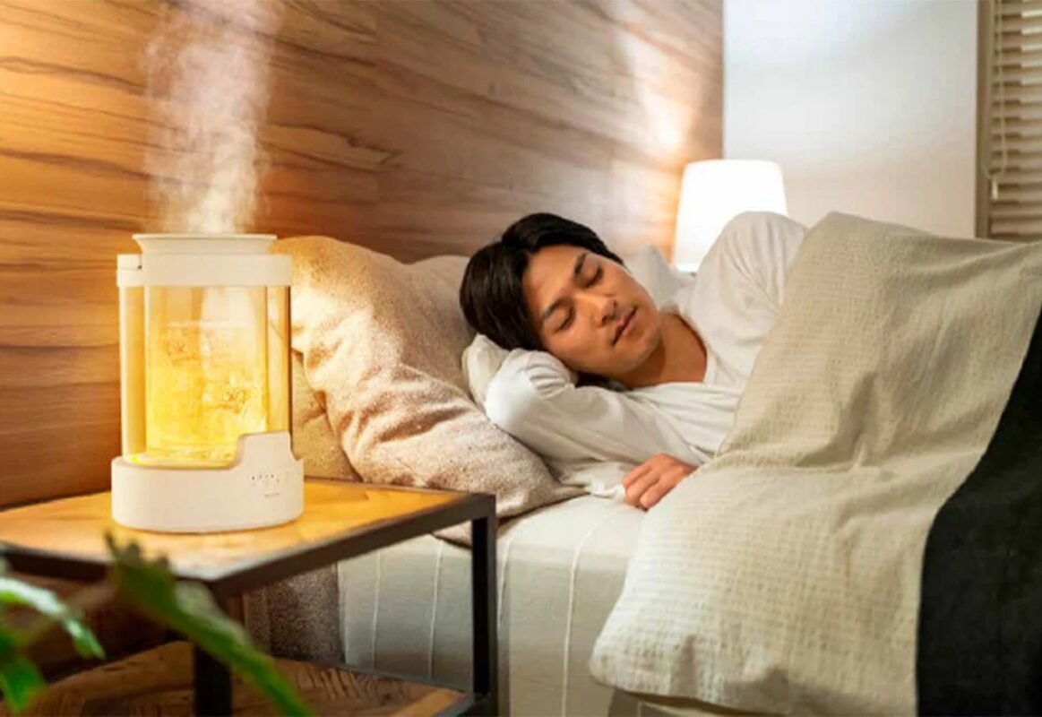 寝室で加湿器を使用する男性