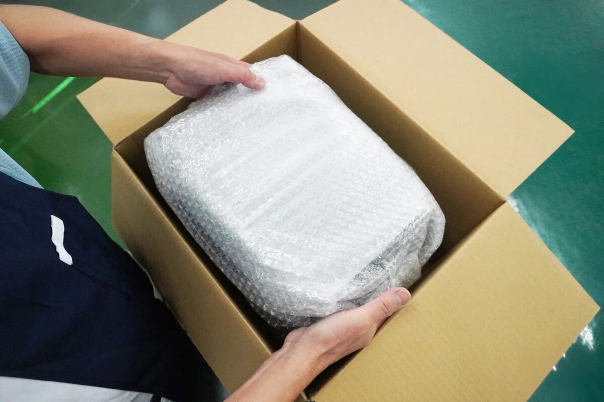 緩衝材で包まれた荷物を段ボール箱に入れる様子