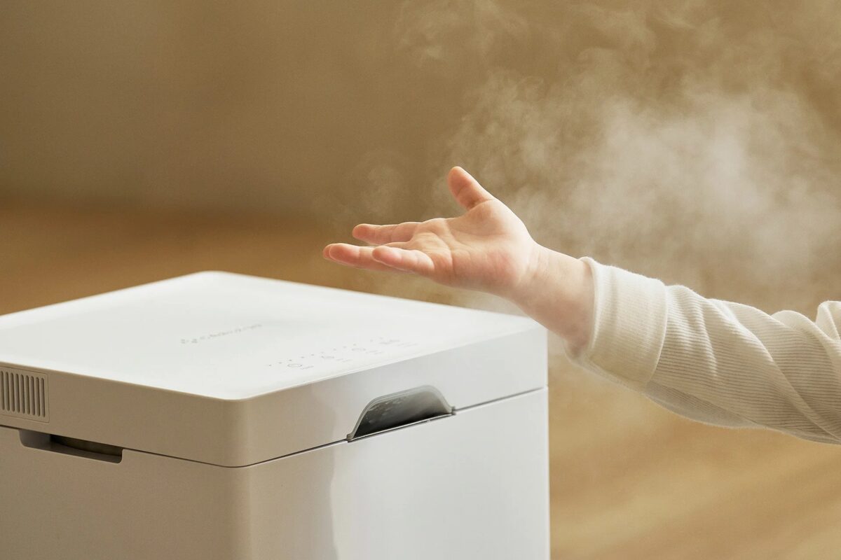 白い家電製品からミストが放出されており、その上に手が差し伸べられています